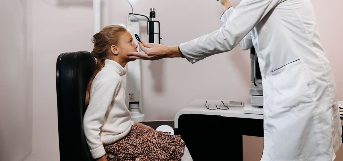 Médico examinando os olhos de uma criança com lanterna clínica durante consulta